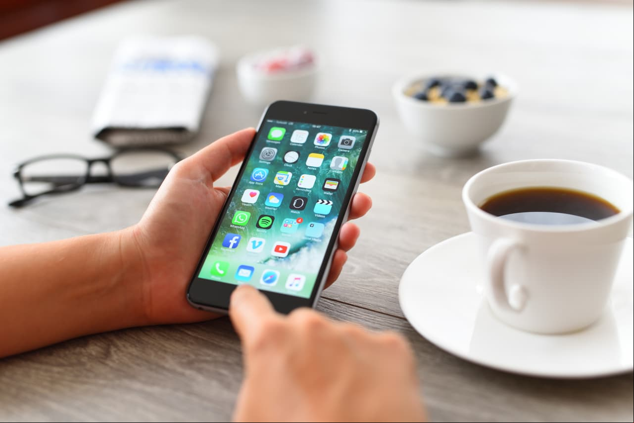 ?stanbul, Turkey - August 15, 2017: Woman using smart phone on a wooden desk. The smart phone is an iPhone 6 plus. iPhone is a touchscreen smartphone developed by Apple Inc.