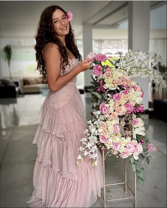 La festejada acompañó su atuendo con un maquillaje tenue y una rosa en el cabello, el cual lució suelto, resaltando sus rizos.