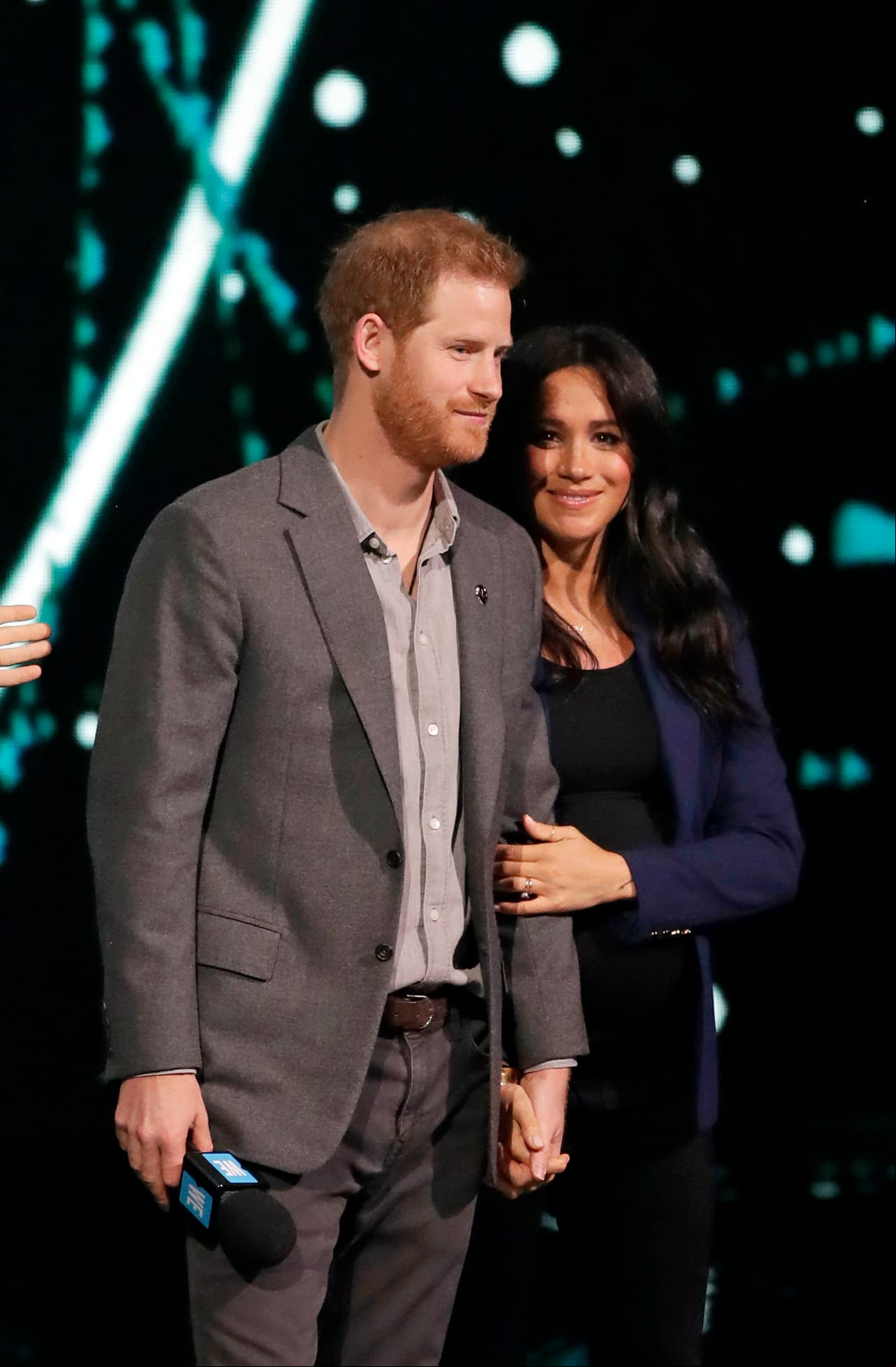 De la mano de Harry, Markle saludó tímida a la audiencia luciendo pantalón, t shirt y zapatillas oscuras que combinó con un blazer azul.
