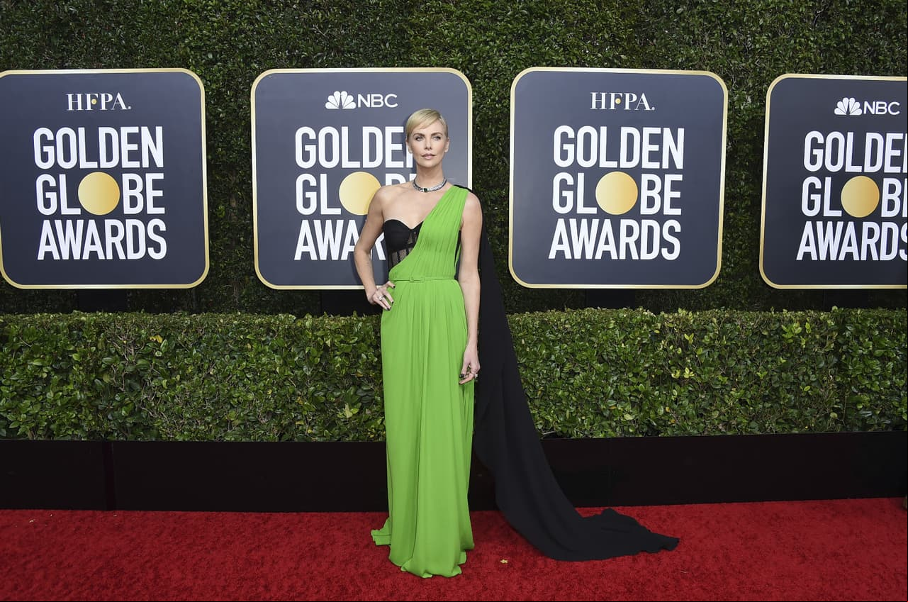 Charlize Theron optó por un diseño asimétrico de Dior en color verde con una capa negra.