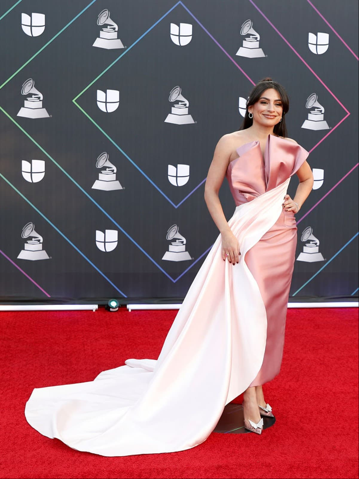 Otra que robó miradas en los Latin Grammy 2021 fue Ana Brenda Contreras al desfilar por la alfombra roja con un despampanante vestido en tono rosa flamingo con detalles de pliegues en el busto, armonizando el resto de su look con un tono más pálido, que comienza por la cintura y termina en una cola de sirena.