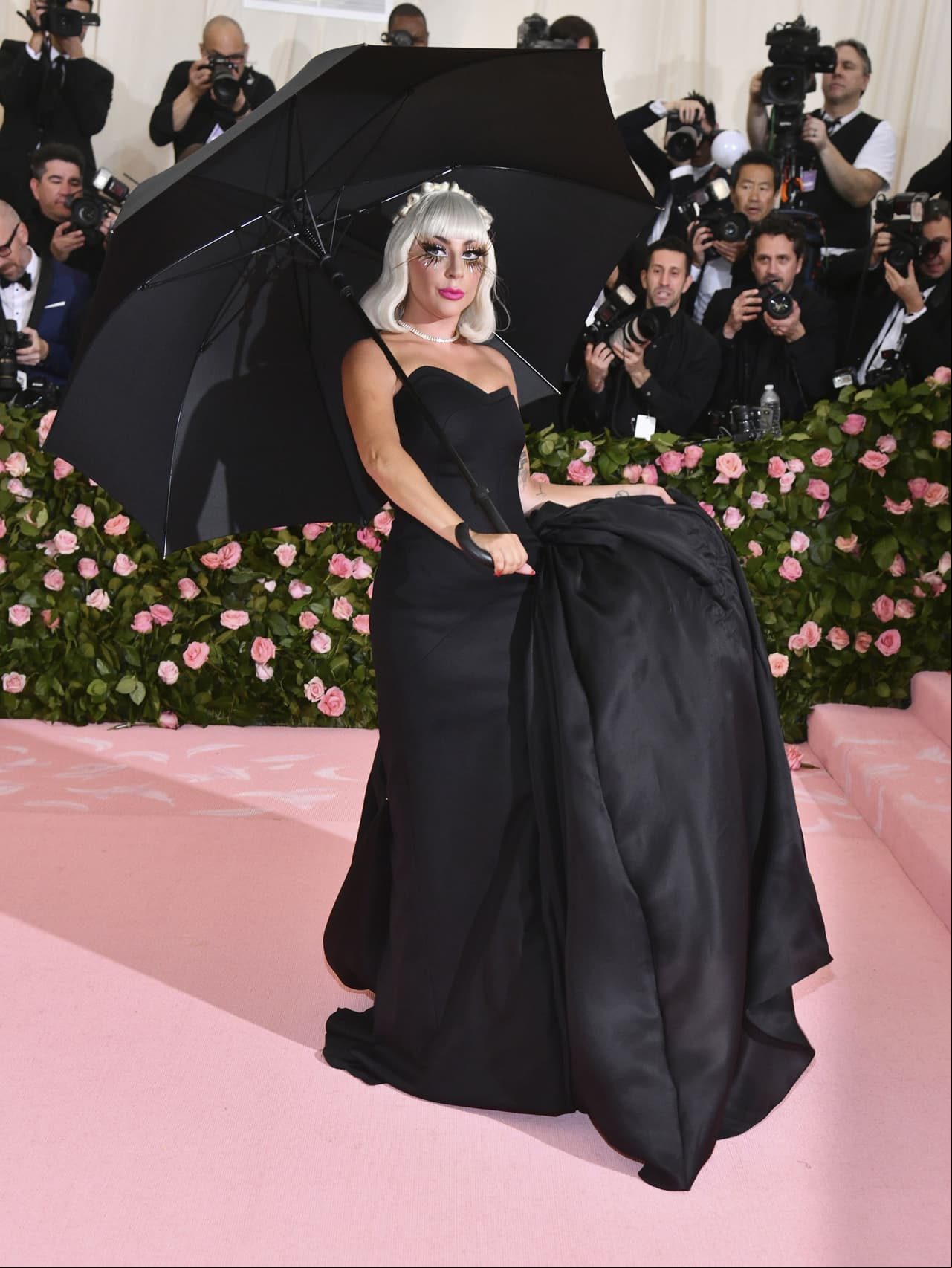 Debajo del diseño tipo capa, Gaga portaba un vestido negro con corsé y guantes.