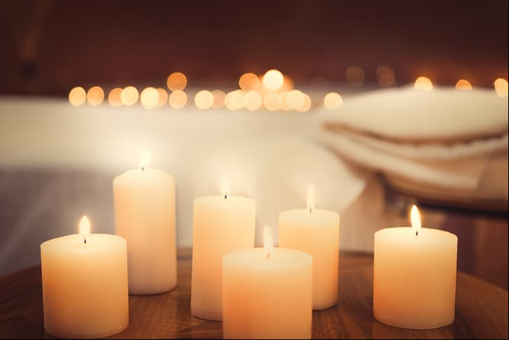 Close up of candles fire on small table. Bed for massage on background