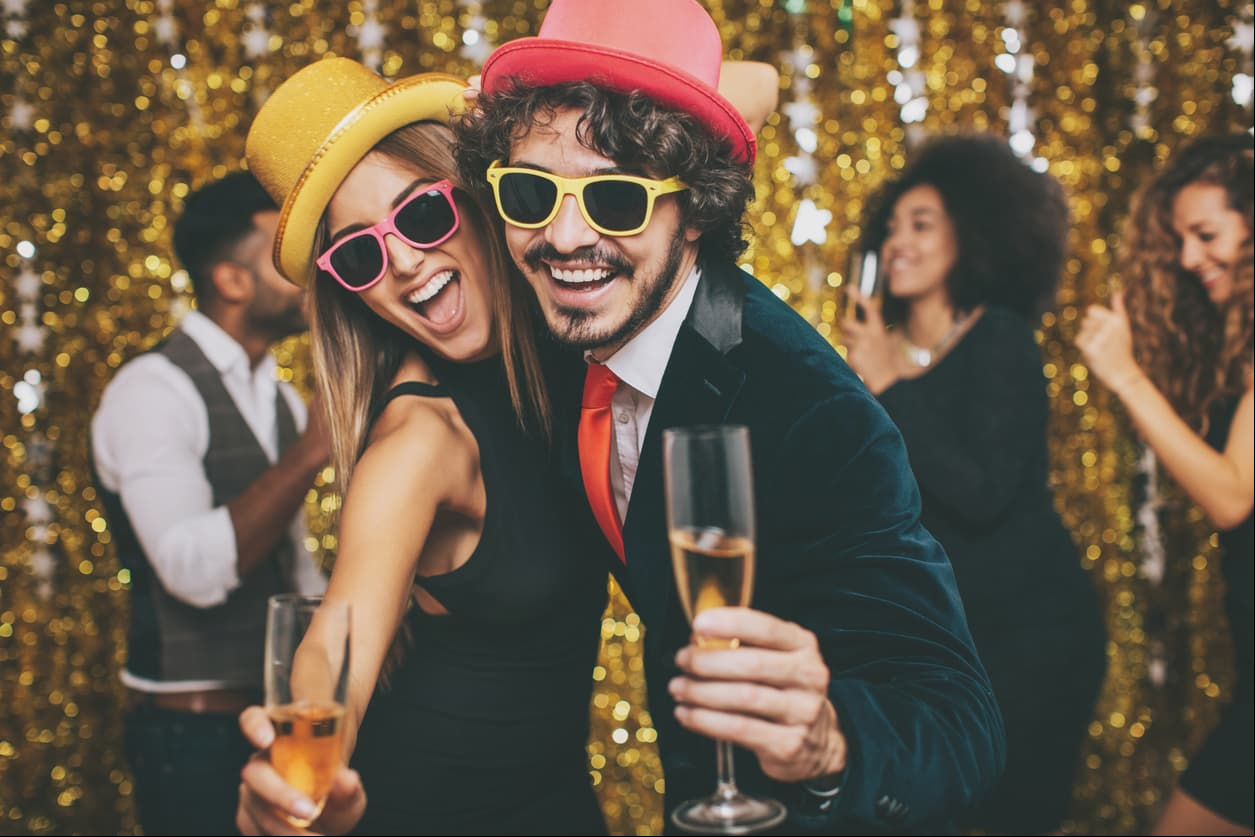 Couple having fun on a formal party, with friends on the background.