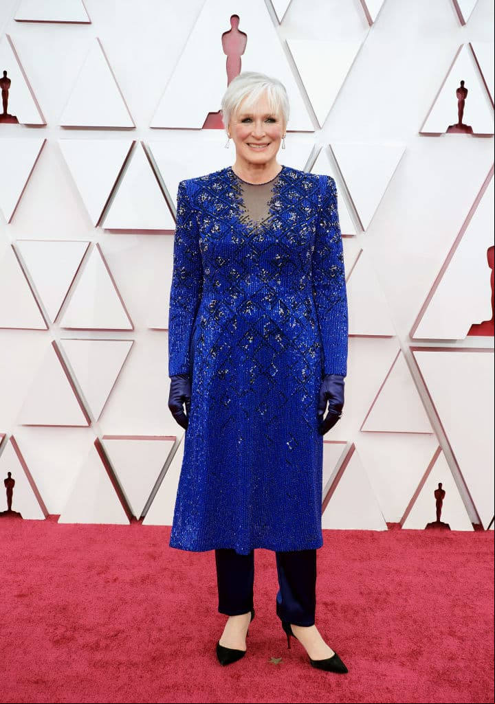 Glenn Close desfiló por la alfombra roja con un vestido azul con incrustaciones en tono plata y unos pantalones negros abajo; su outfit lo complementó con unos guantes en tono azul y zapatillas negras.